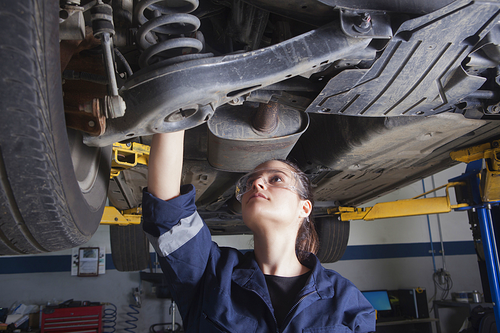 Hispanic mechanic repairing car