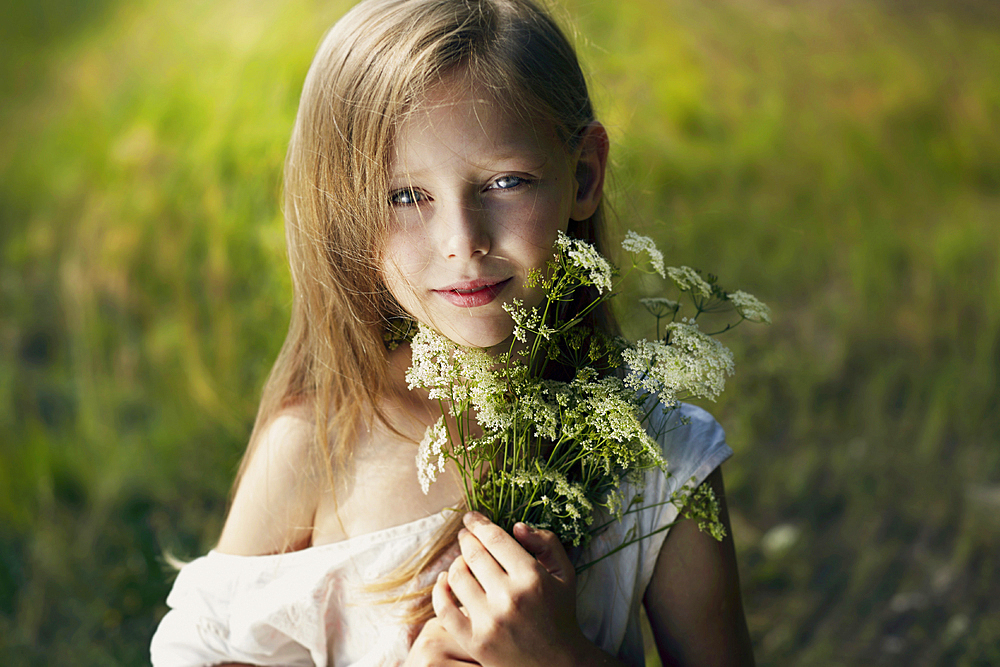 Caucasian girl holding bouquet of wildflowers