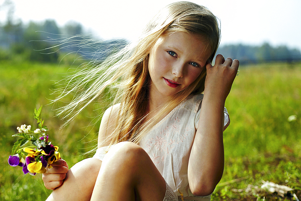 Caucasian girl holding flowers in windy field