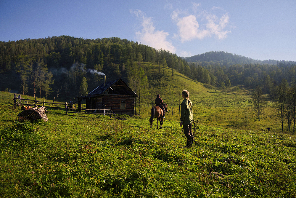 Caucasian girl watching girl riding horse