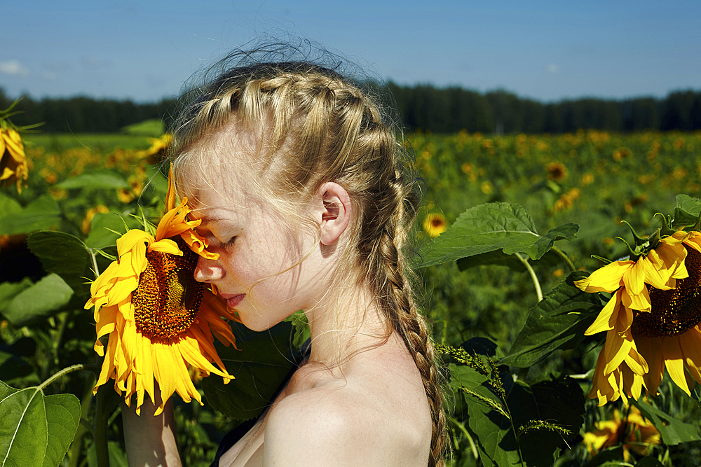 Caucasian girl smelling sunflower