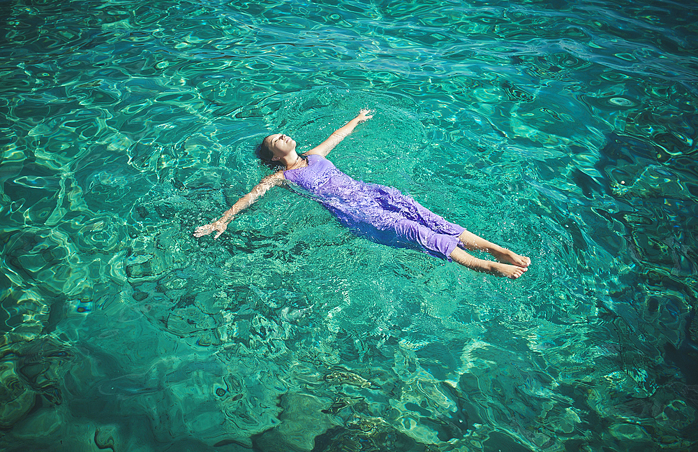 Caucasian woman wearing dress floating in water