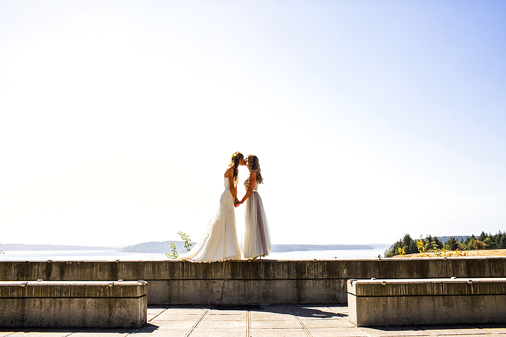 Caucasian brides kissing at waterfront