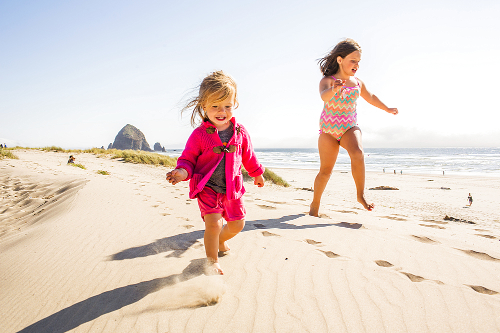 Caucasian sisters running on beach