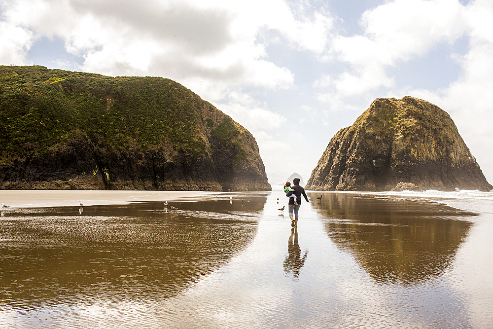 Caucasian mother carrying daughter on beach