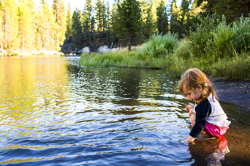 Caucasian girl crouching in river