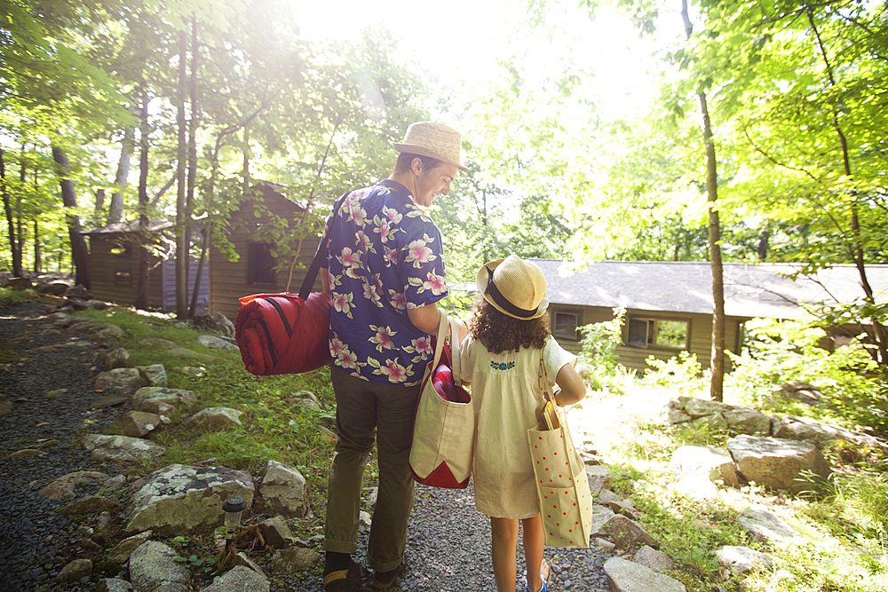 Caucasian father and daughter carrying bags at cabin