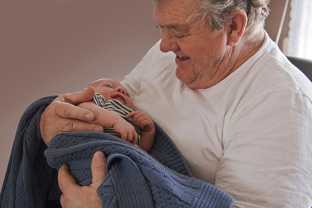 Caucasian grandfather holding baby grandson