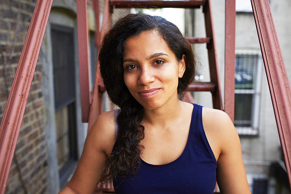 Portrait of smiling woman sitting on urban fire escape