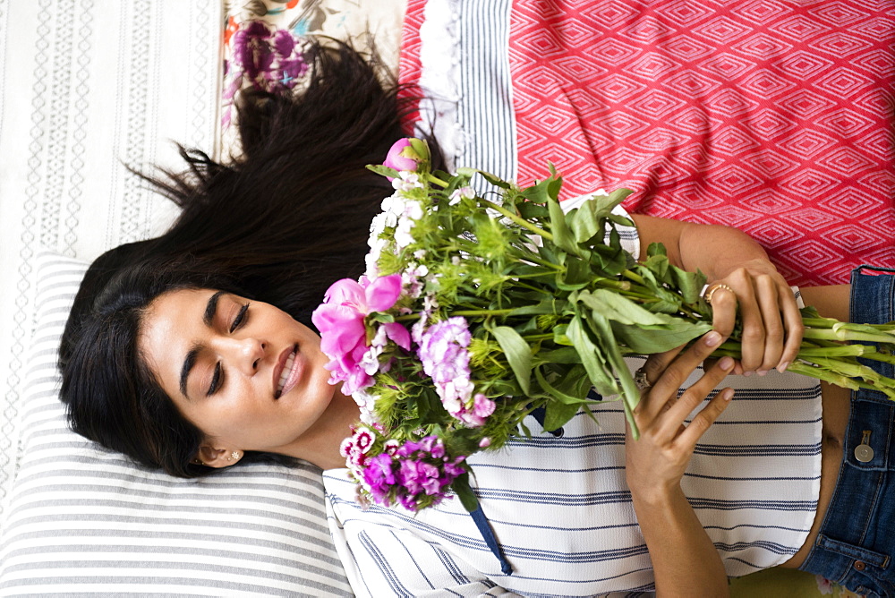 Indian woman laying on bed holding bouquet of flowers