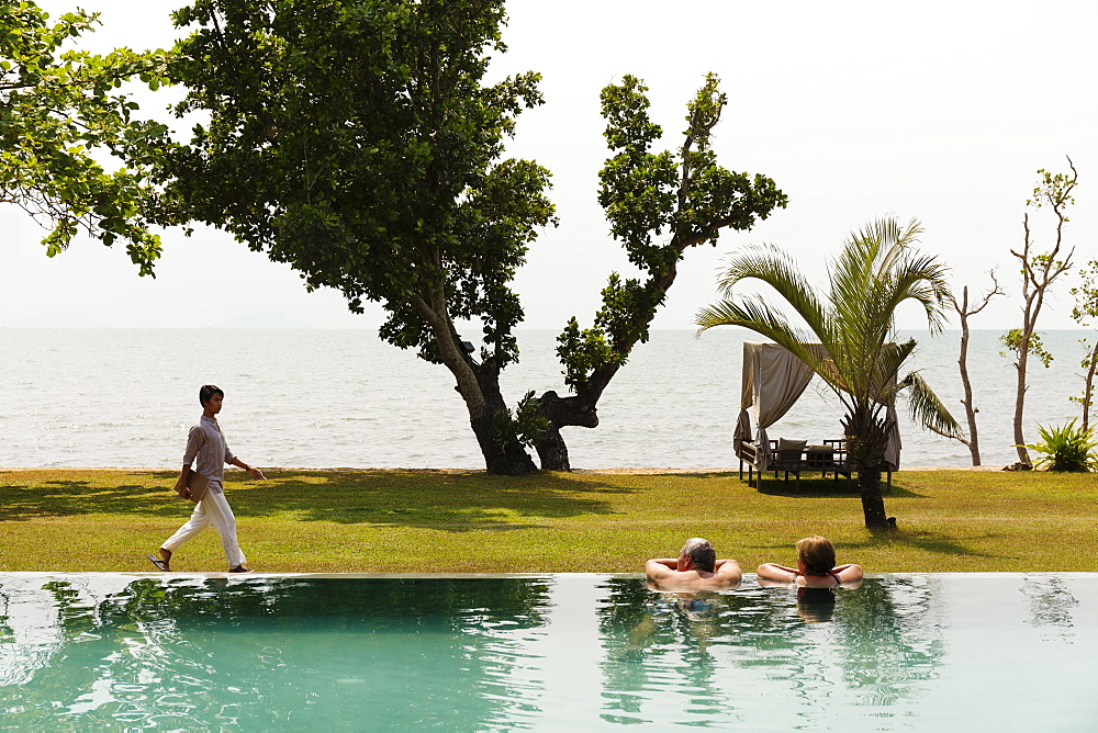 Couple swimming in luxury pool near ocean