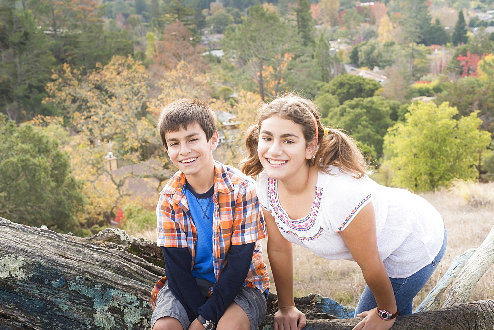 Mixed Race brother and sister posing on log