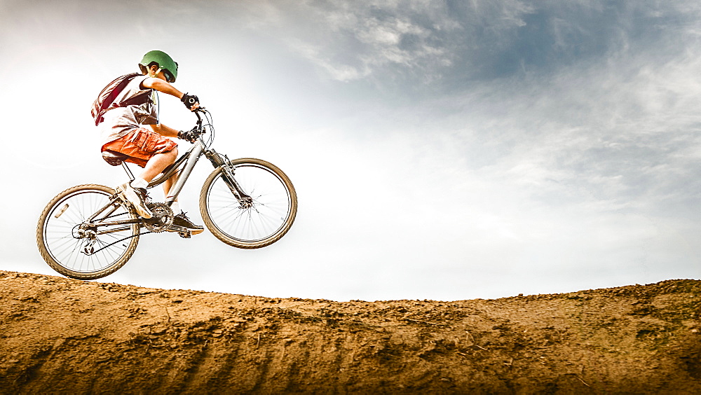 Mixed race boy riding dirt bike on track