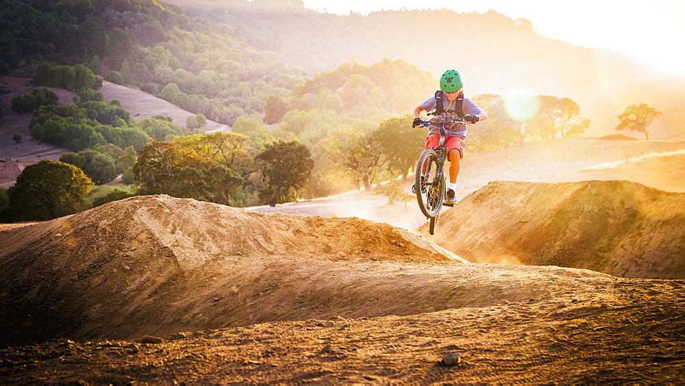 Mixed race boy riding dirt bike on track