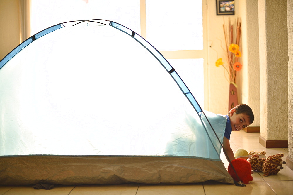 Hispanic boy camping in tent indoors