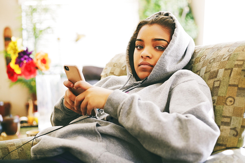 Mixed Race woman sitting on chair listening to cell phone