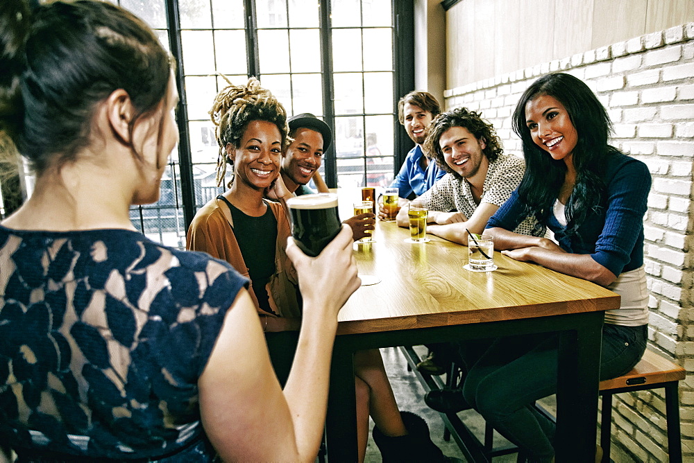 Waitress serving smiling friends at table in bar