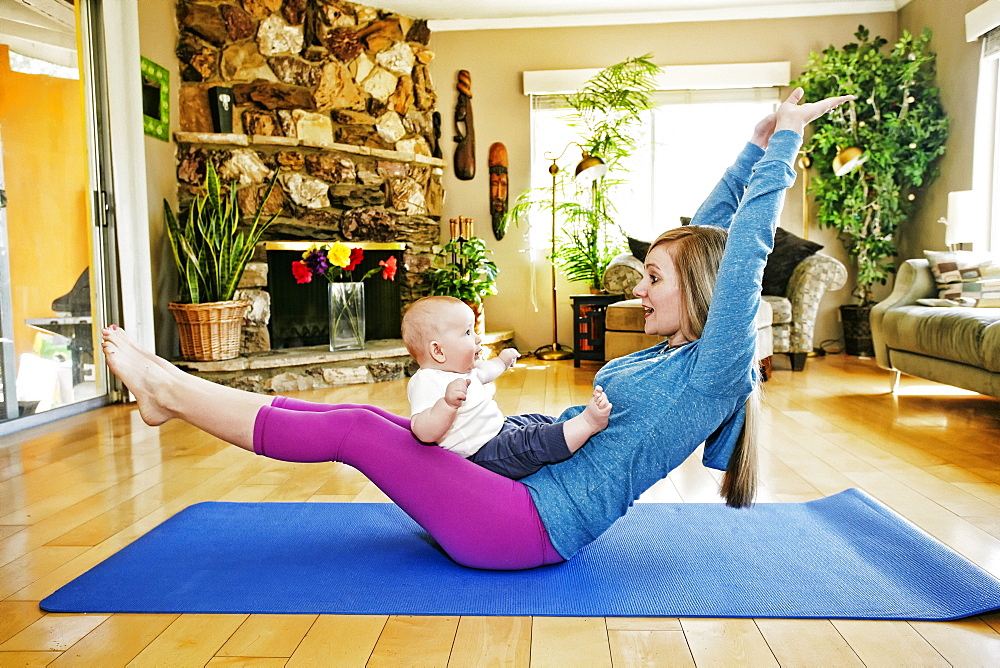 Mother working out on exercise mat with baby in lap