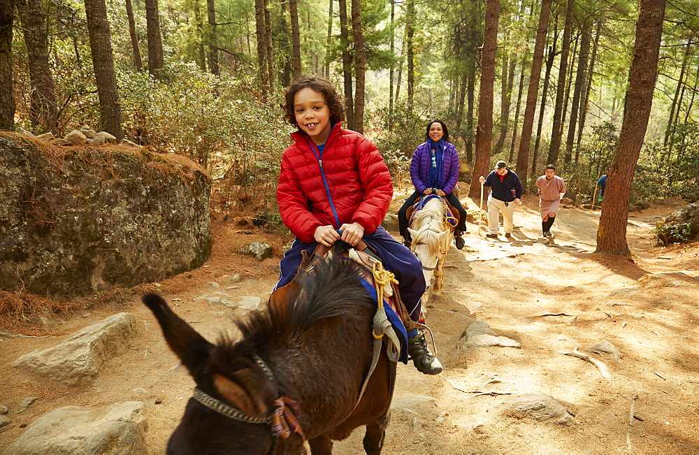 Mixed Race mother and son riding horses