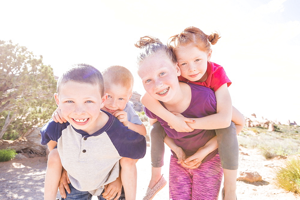 Caucasian children carrying boy and girl piggyback