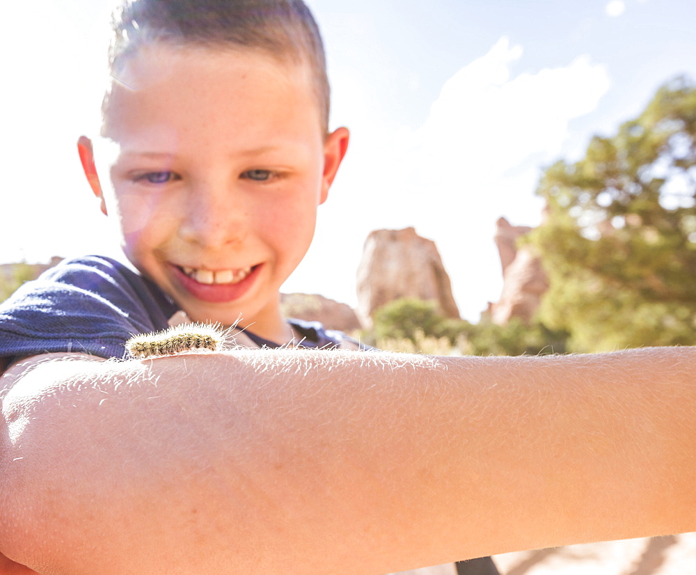 Caucasian boy watching caterpillar crawl on arm