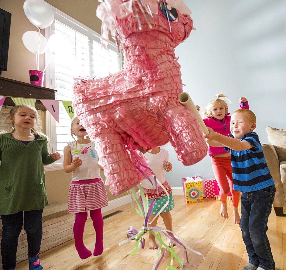 Caucasian boy hitting pinata at party