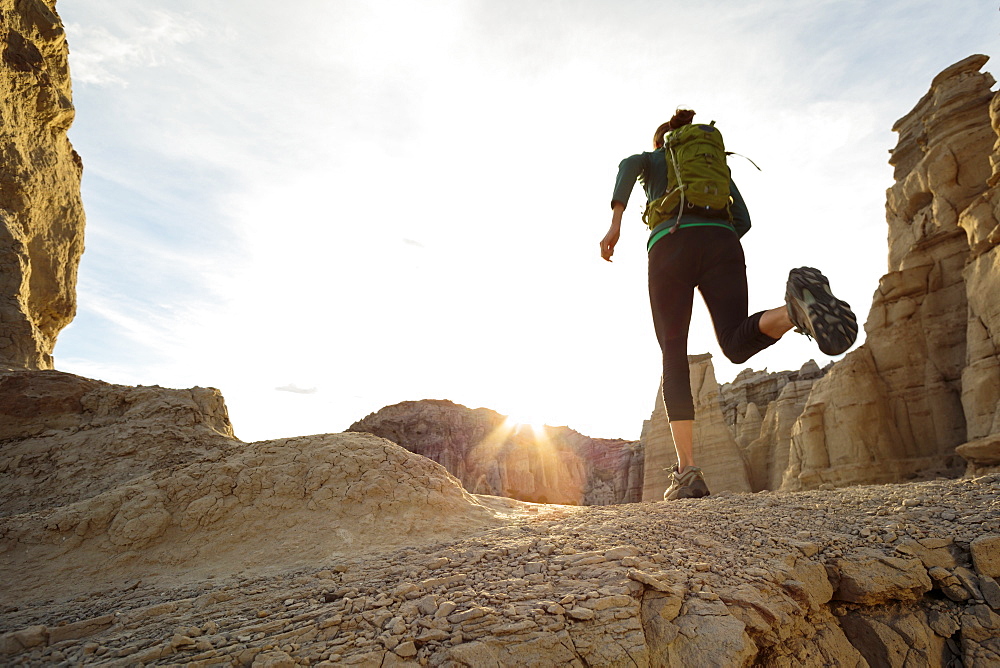 Woman running in canyon wearing backpack