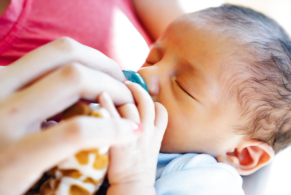 Hispanic woman holding baby boy with pacifier