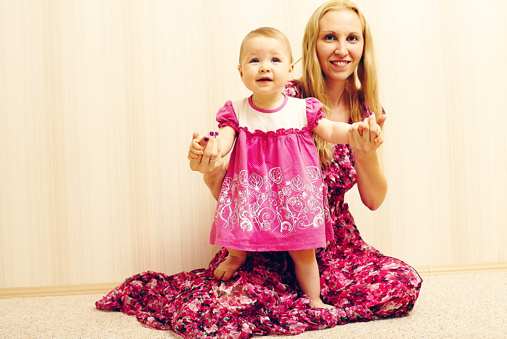 Caucasian mother helping baby daughter walk