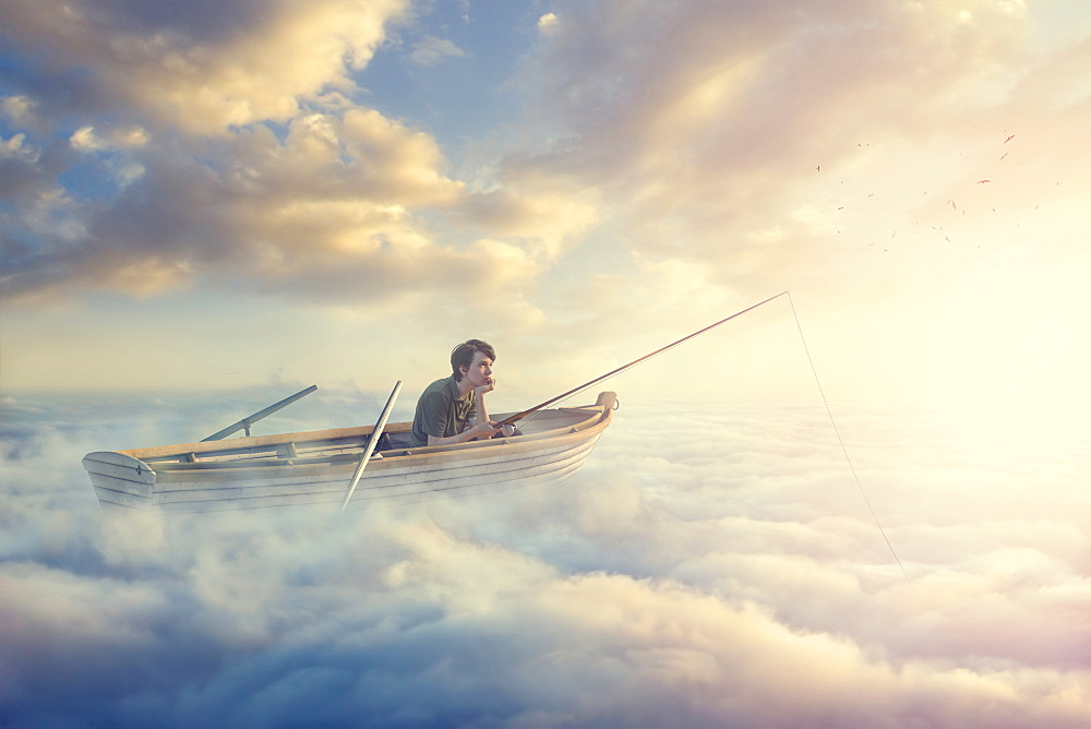 Caucasian boy fishing on rowboat in clouds