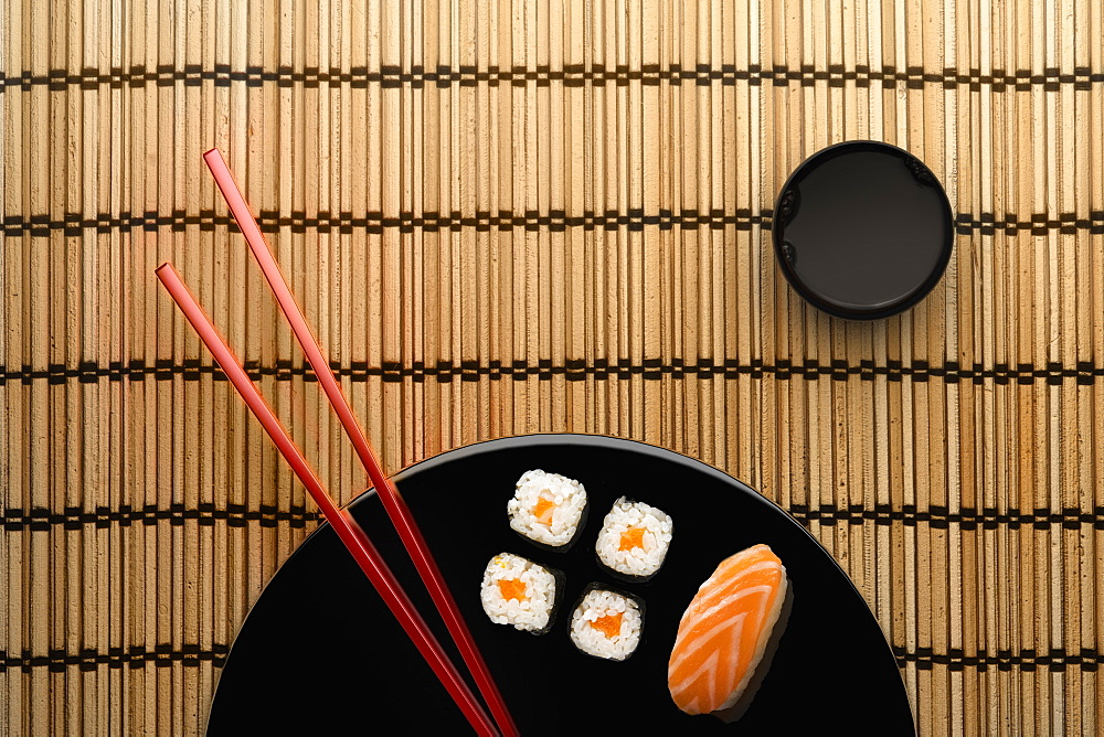 Chopsticks and sushi on round plate with dipping sauce