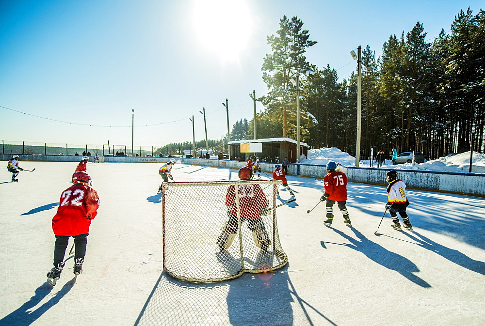 Caucasian boys playing ice hockey outdoors