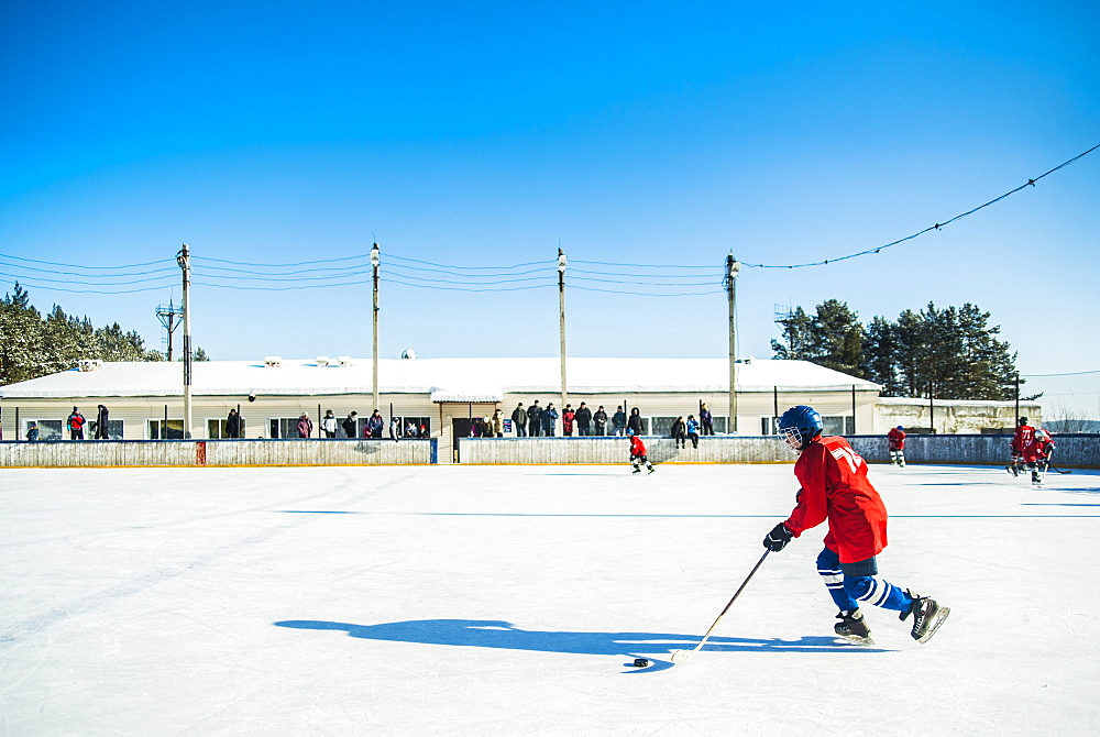 Caucasian boys playing ice hockey outdoors