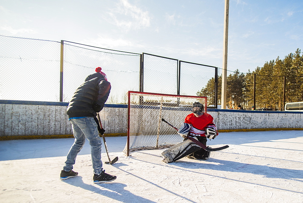 Caucasian boys playing ice hockey outdoors