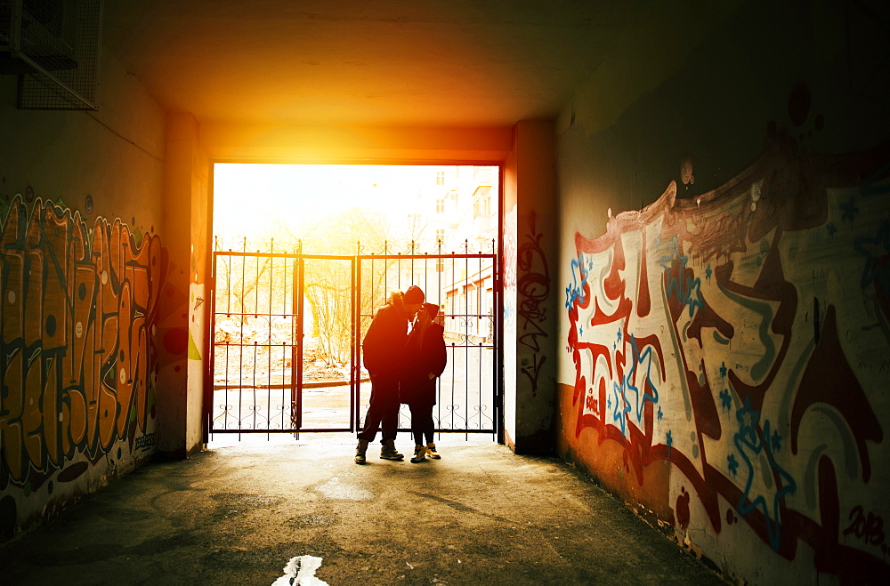 Couple kissing near graffiti at urban gate