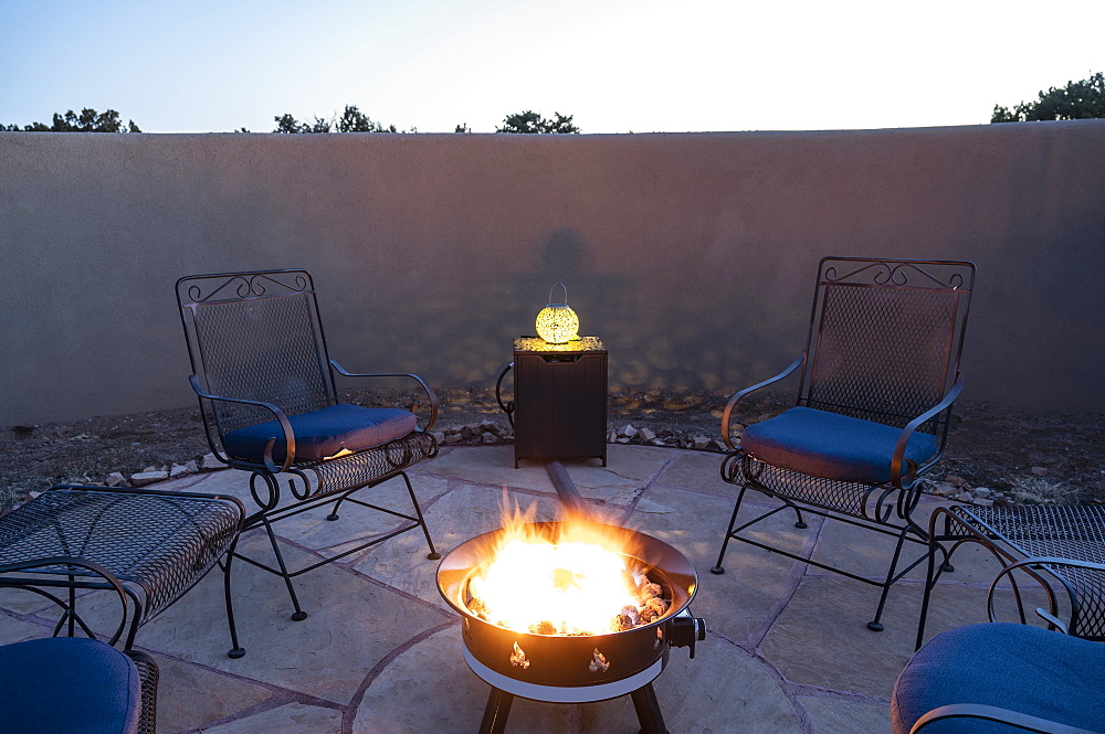 Chairs around back yard fire pit at dusk