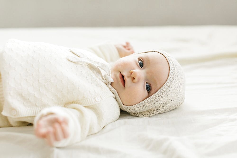 Baby boy (2-5 months) lying on bed