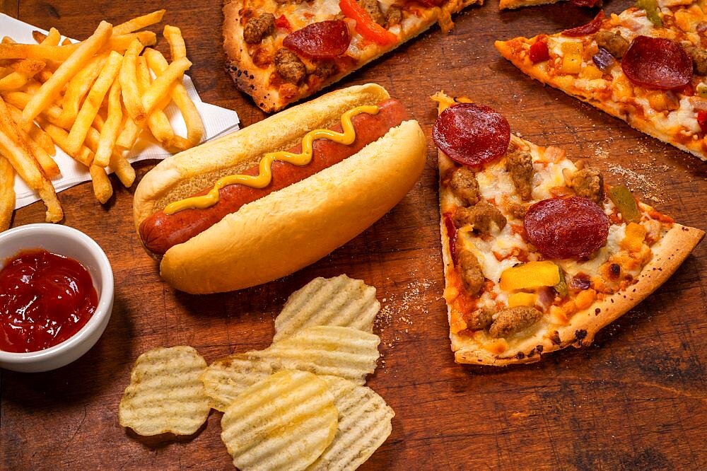 Variety of processed foods with pizza, hot dog, chips, and french fries