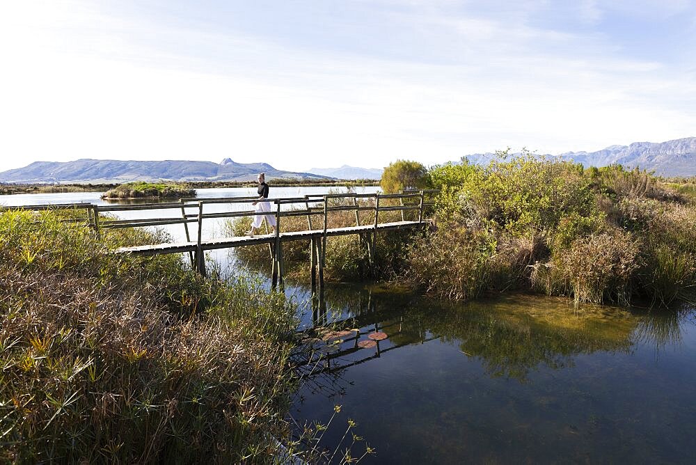 South Africa, Stellenbosch, Teenage girl (16-17) walking on wooden footbridge