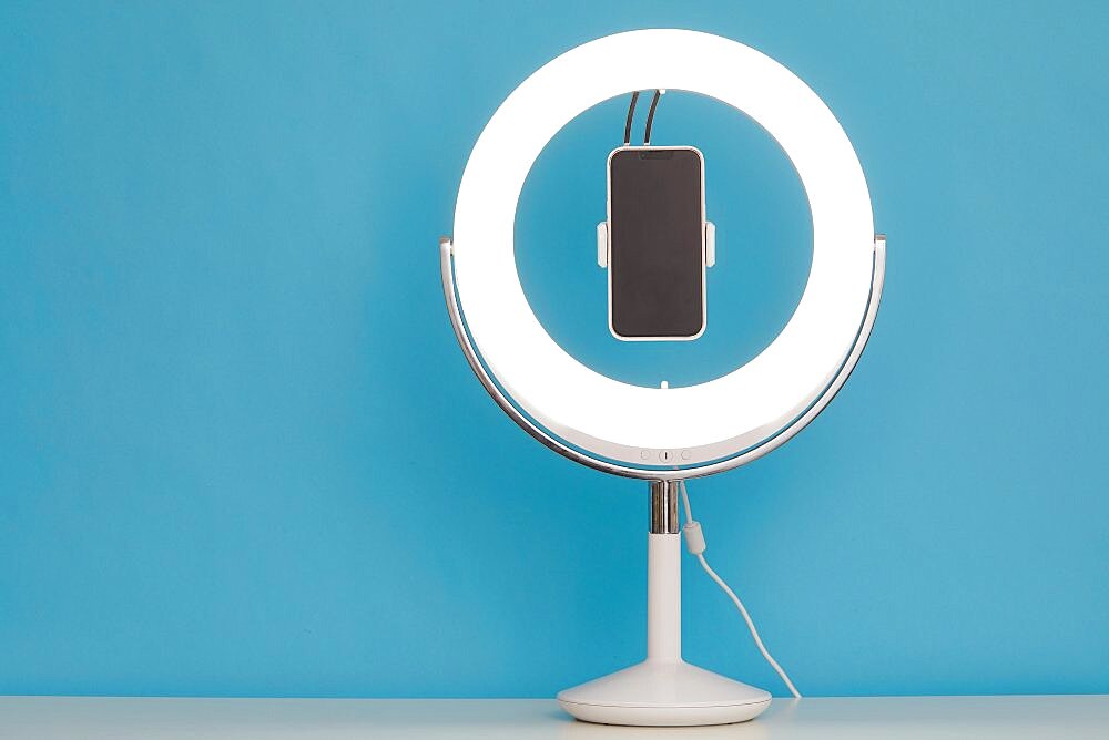 Ring light and smart phone on blue background