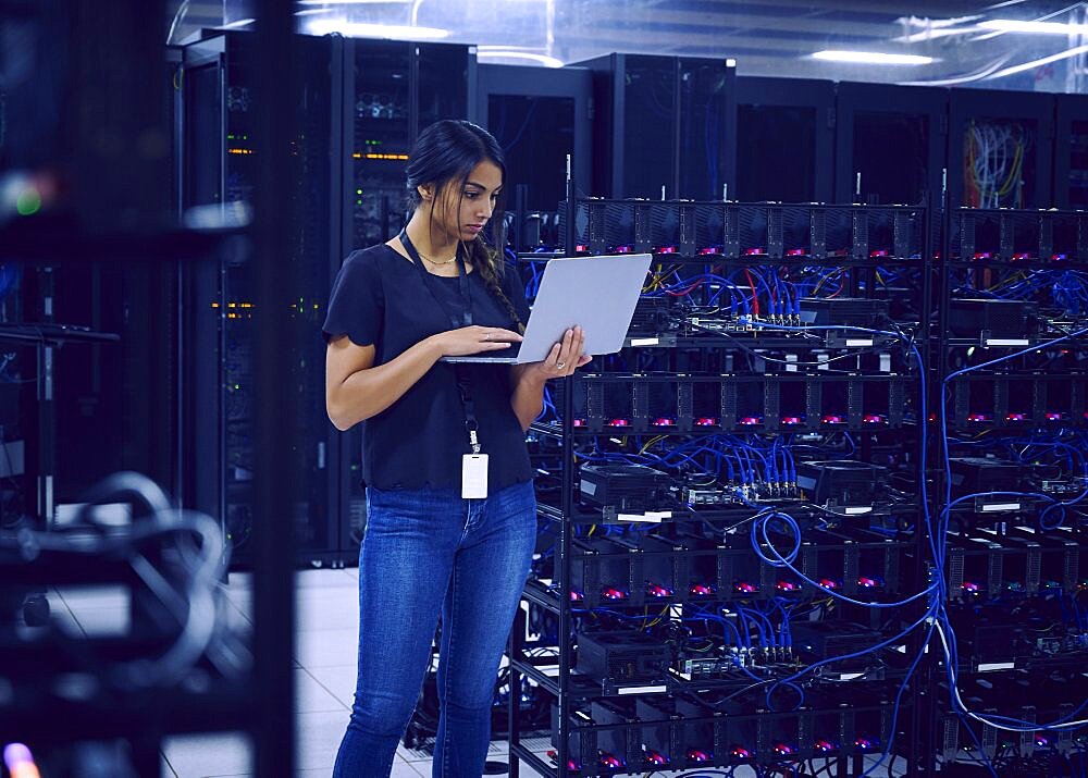 Female technician using laptop in server room