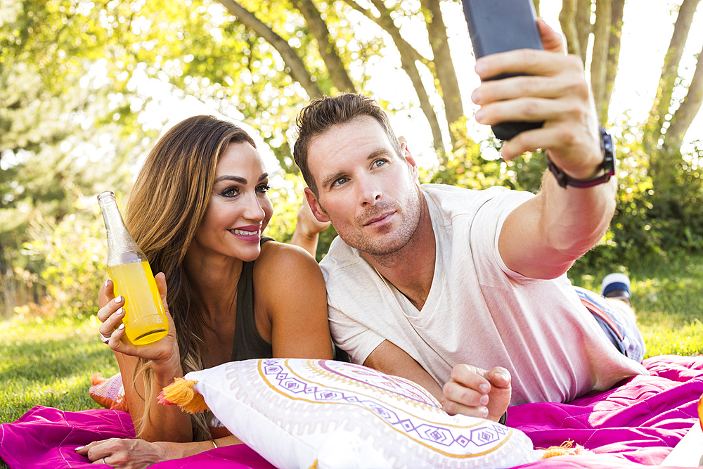 Man taking picture with smart phone at picnic in park
