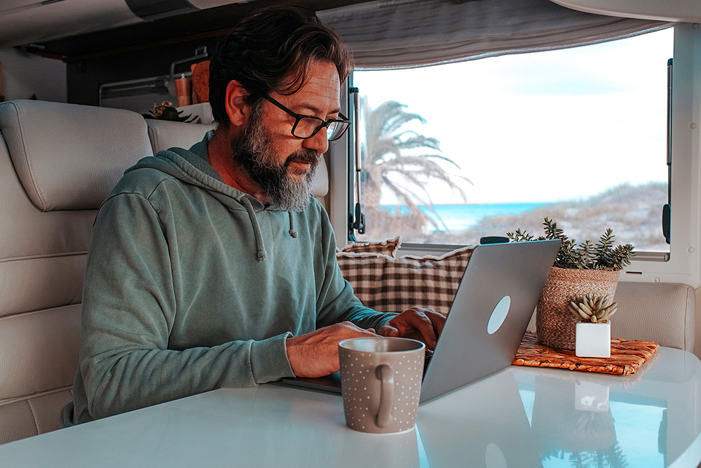 Man sitting in mobile home and working on laptop