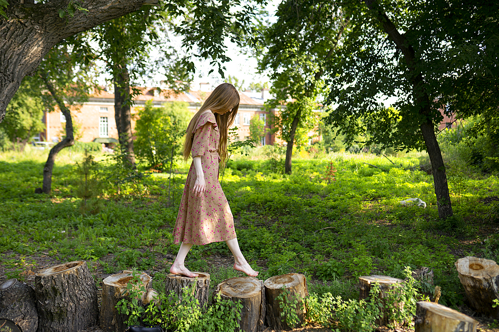 Young woman walking on tree stumps