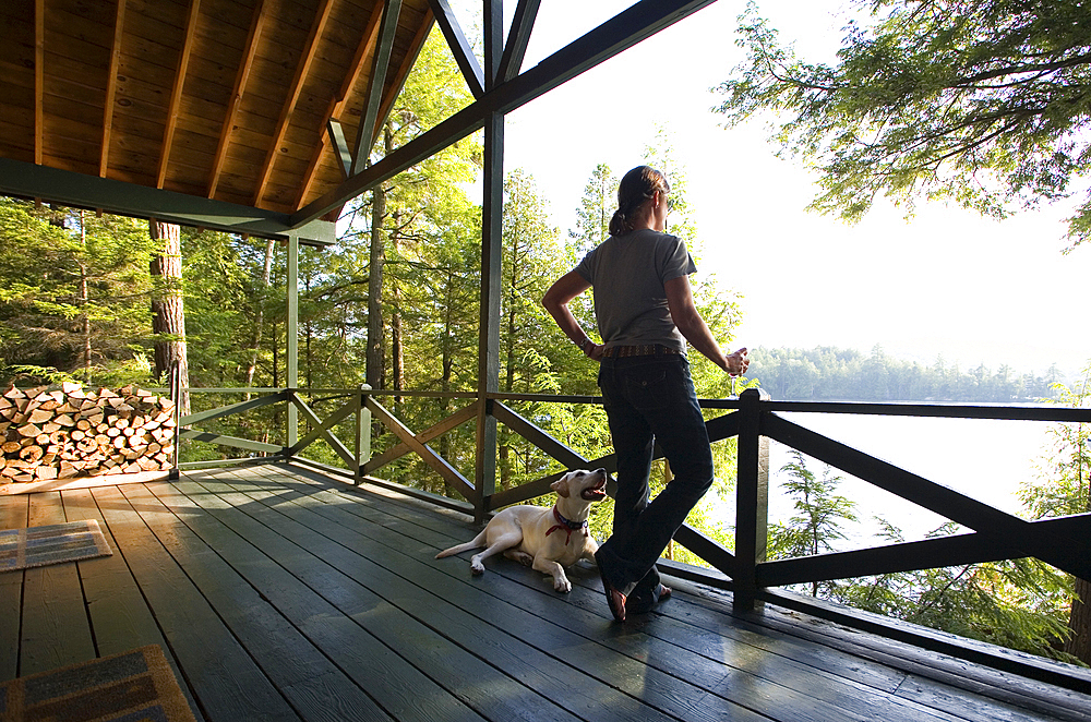 Woman with dog looking at lake from porch