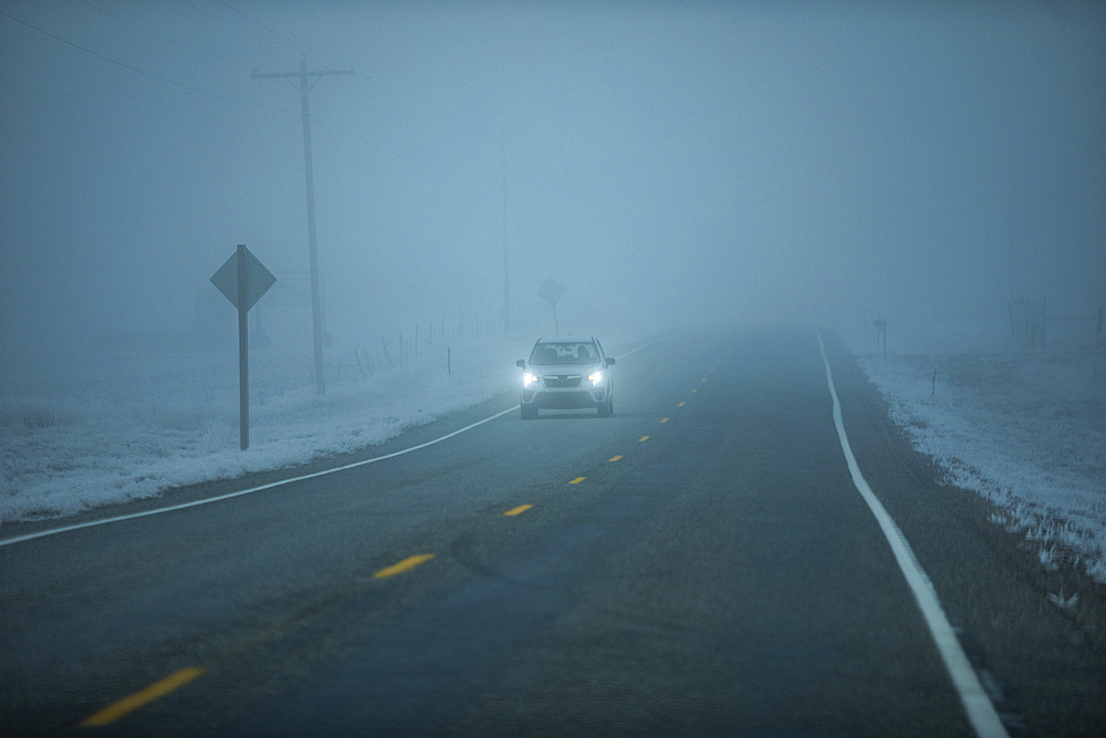 Car on Idaho 20 road in heavy fog at dusk
