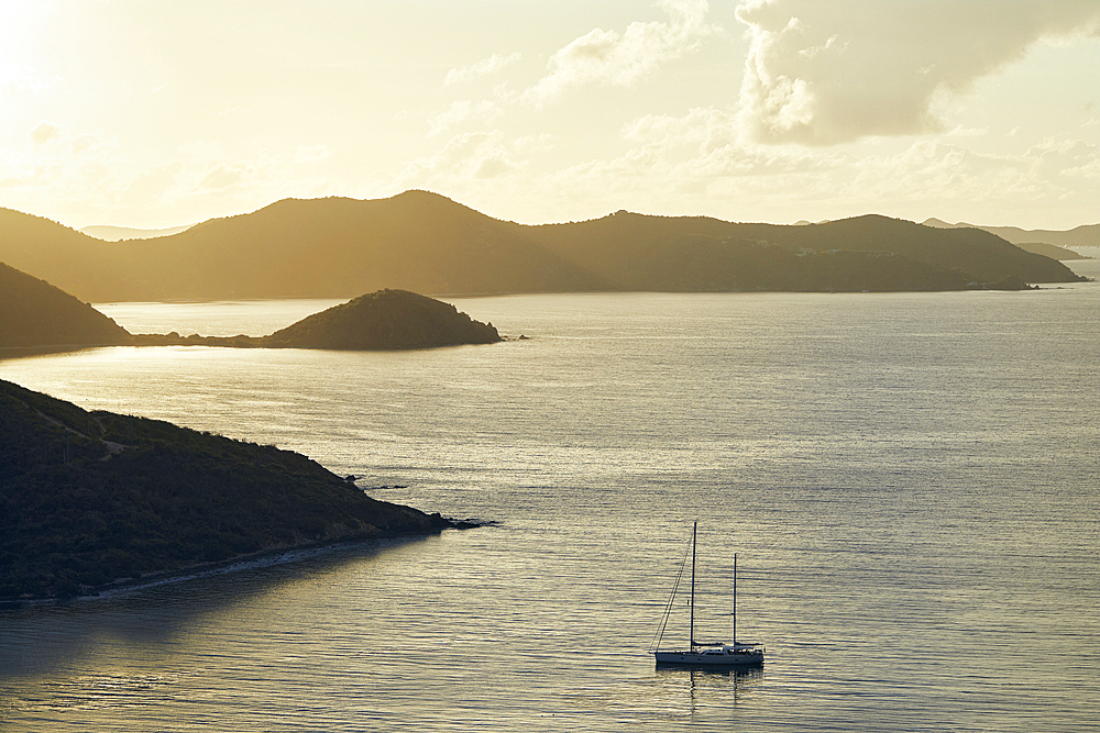 Sailboat anchored on calm bay at sunrise