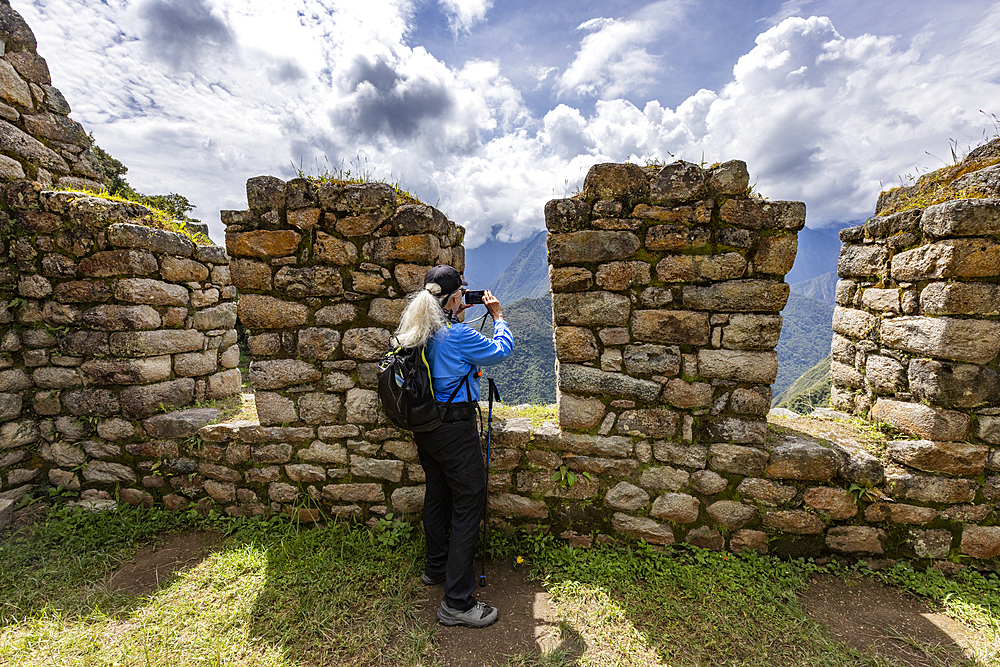 Woman hiker taking photos with smart phone at Machu Picchu