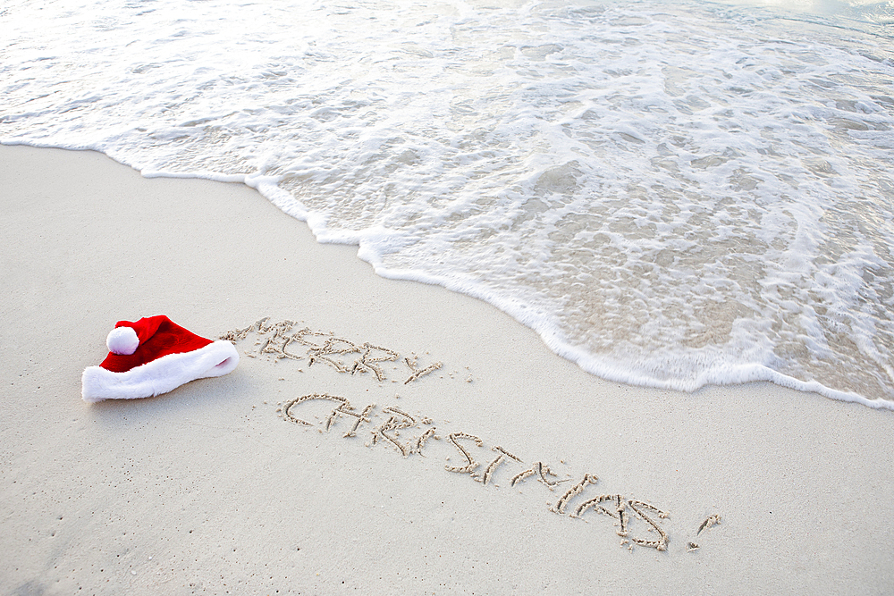 Santa hat and Christmas greetings written in beach sand, St. John, United States Virgin Islands, USA