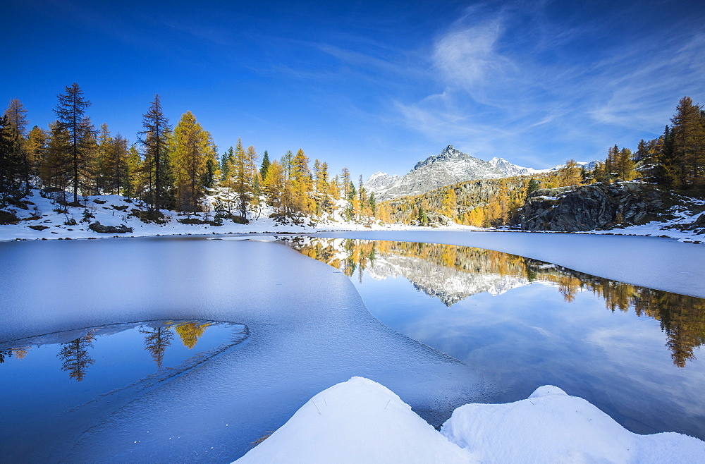 The peaks of Valmalenco in Valtellina reflecting in the water of the half frozen Lake Mufule, Lombardy, Italy, Europe